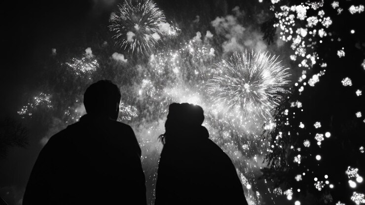 Dos personas viendo un colorido espectáculo de fuegos artificiales en un cielo nocturno perfecto para celebraciones o eventos