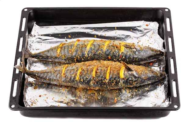 Dos pescados de mar crudos listos para cocinar en una fuente para hornear con papel de condimento y rodajas de limón