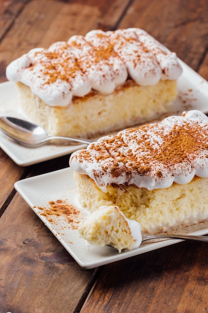 Dos piezas de un delicioso postre de tarta de tres leches sobre un fondo de madera