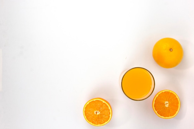 Dos piezas de naranjas jugosas con un vaso de naranja aislado en la vista superior de fondo blanco de BG