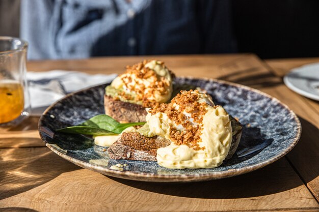 Dos piezas de pan de centeno integral tostado con puré de huevos escalfados con aguacate y salsa