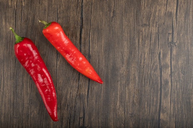 Dos pimientos rojos colocados sobre una superficie de madera