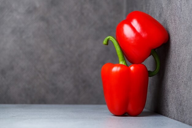 Dos pimientos rojos sobre una mesa gris