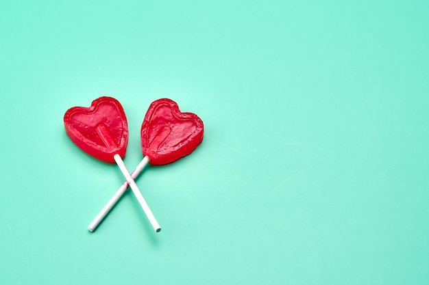 Foto dos piruletas en forma de corazón en un fondo verde que representan el amor