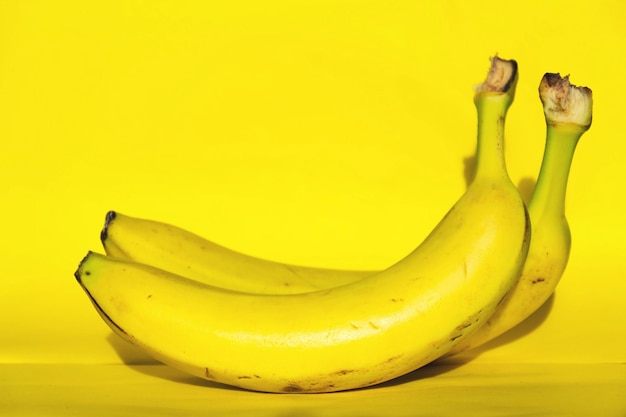 Dos plátanos frescos amarillos que yacen aislados en una dieta saludable de fondo amarillo