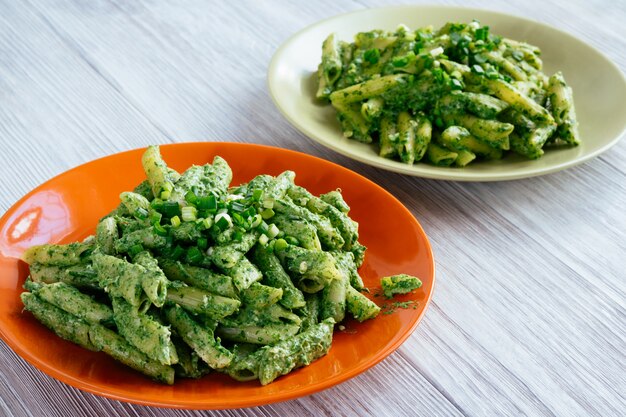 Dos platos con pasta de espinacas en una mesa de madera blanca