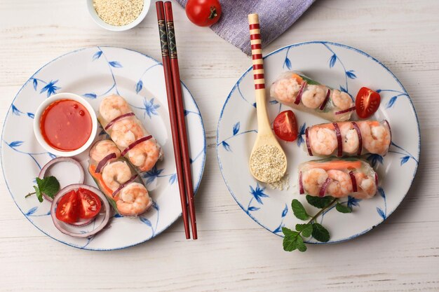 Dos platos de rollo de primavera vietnamita hechos de papel de arroz con camarones y verduras servidos con salsa roja Vista horizontal desde arriba