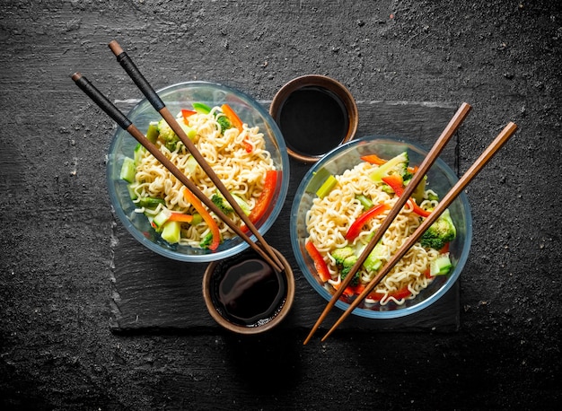 Dos porciones de fideos instantáneos con brócoli, pimiento y pepino