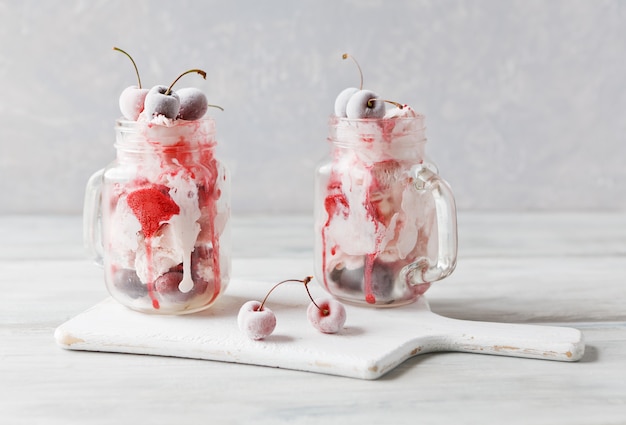 Dos porciones de helado en tazas de vidrio con cereza congelada.