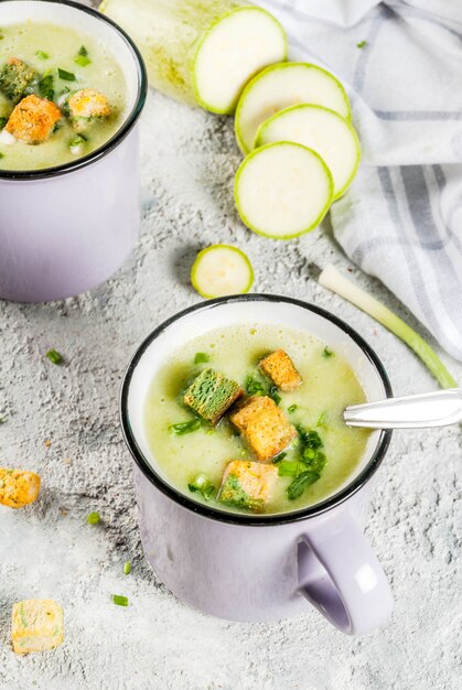 Dos porciones de sopa cremosa de calabacín casera con migas de pan en tazas