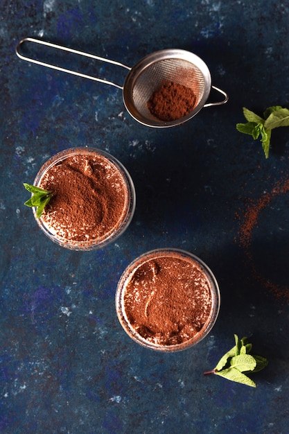 Dos porciones de tiramisú adornado con cacao y menta