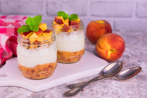 Foto dos porciones de yogur con melocotón sobre un fondo gris