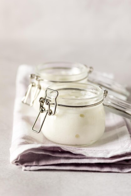 Dos porciones de yogur orgánico natural fresco en frascos de vidrio sobre una servilleta de yogur griego casero Vertical