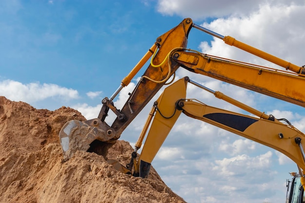 Dos potentes excavadoras trabajan al mismo tiempo en un sitio de construcción cielo azul soleado en el fondo Equipos de construcción para movimiento de tierras