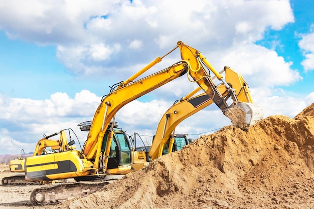 Dos potentes excavadoras trabajan al mismo tiempo en un sitio de construcción cielo azul soleado en el fondo Equipos de construcción para movimiento de tierras