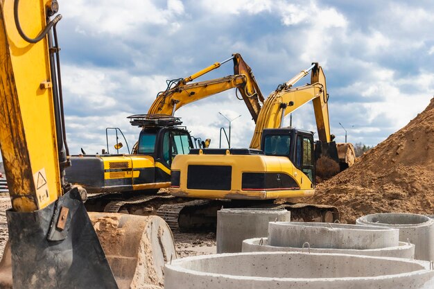 Dos potentes excavadoras trabajan al mismo tiempo en un sitio de construcción cielo azul soleado en el fondo Equipos de construcción para movimiento de tierras