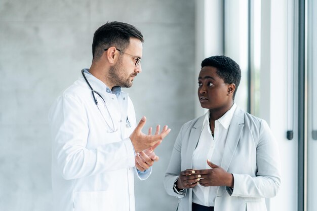 Foto dos profesionales de la salud negros discuten el caso del paciente en una tableta digital