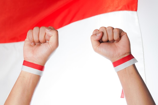 Dos puños celebrando la victoria y la independencia con el fondo de la bandera indonesia
