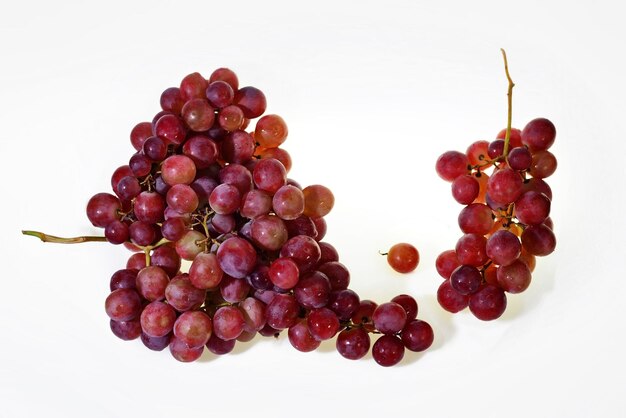 Dos racimos de uvas rosadas de vino fresco que caen aisladas en un fondo blanco