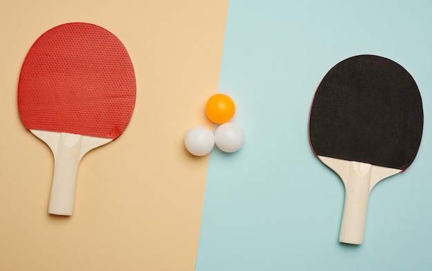 Dos raquetas de madera y pelotas de plástico para jugar tenis de mesa.