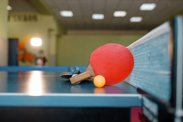 Dos raquetas de ping pong y pelota sobre la mesa con red