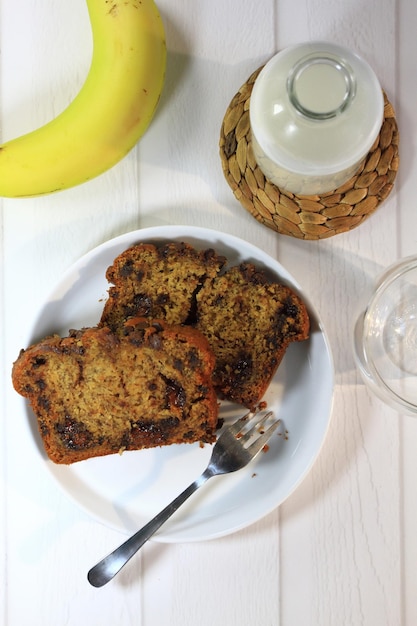 Dos rebanadas de pan de plátano una botella de leche con un vaso y un menú de desayuno de plátano maduro