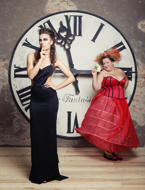 Foto dos reinas posando junto al reloj en una foto navideña