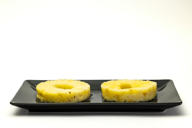 Dos rodajas de piña en un plato negro.