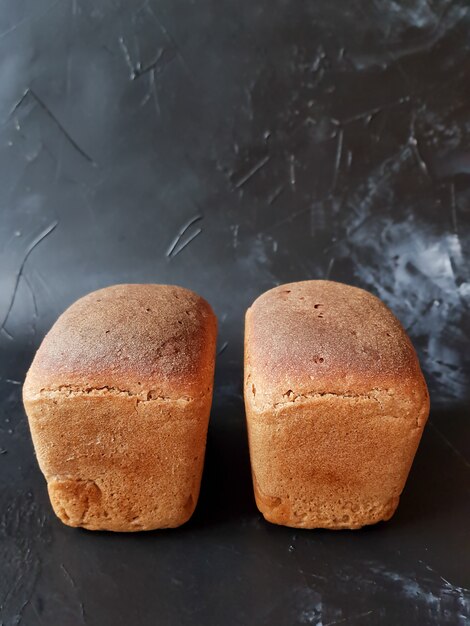 Dos rollos de pan de centeno con levadura de harina sobre un fondo negro, fermentación larga.