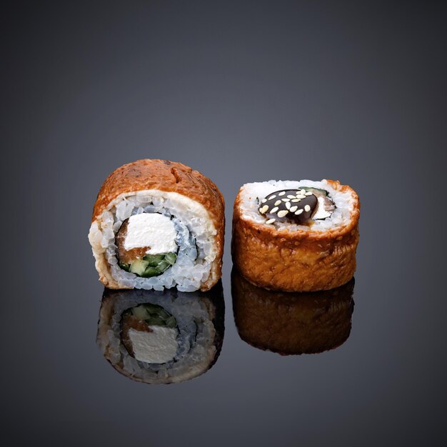 Dos rollos de sushi están sobre un fondo negro con un fondo negro.