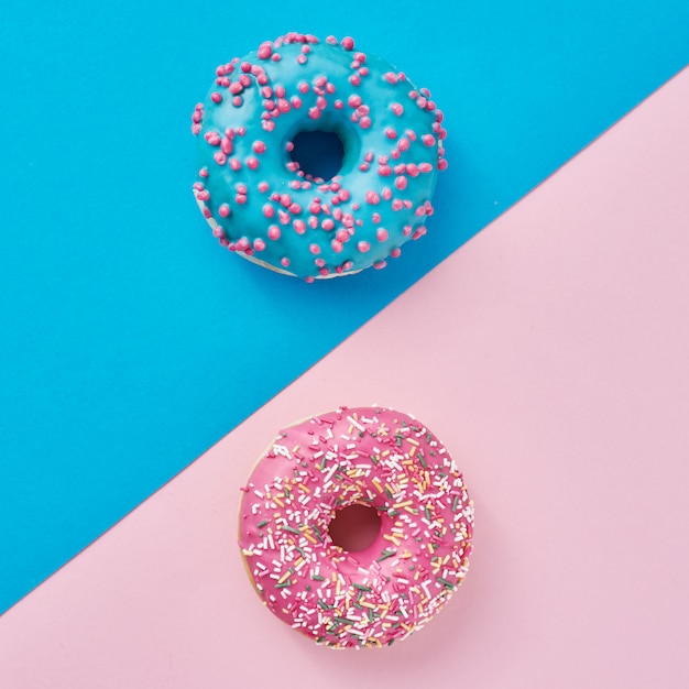 Dos rosquillas en rosa pastel y azul. Minimalismo composición creativa de alimentos. Estilo plano laico