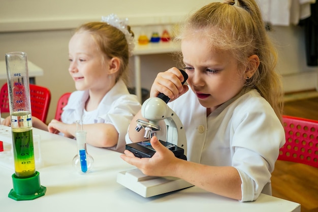 Dos rubias químico escuela niño estudiante niñas (novia hermanas) experimento químico bata médica blanca ciencia en el aula