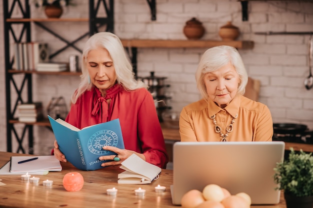 Dos señoras agradables de pelo gris mirando involucrados mientras estudian juntos