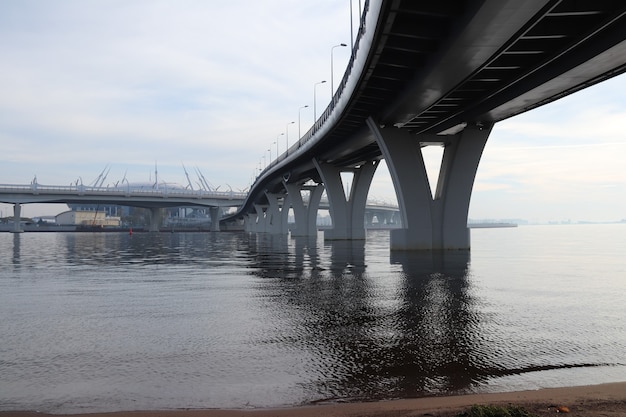 Dos serpenteantes puentes de carretera sobre el ancho río con la niebla vista futurista