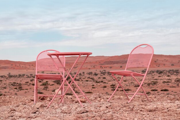 Dos sillas rosadas y una mesa de pie en el desierto de Namib contra el telón de fondo de un cielo nublado