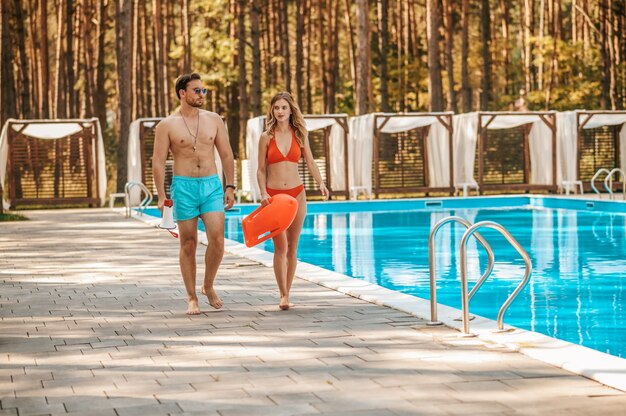 Dos socorristas de la piscina caminando cerca de la piscina pública y hablando