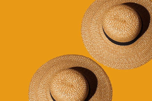 dos sombreros de paja sobre un fondo naranja