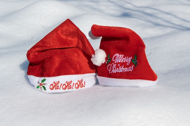 Dos sombreros rojos de Navidad en el concepto de celebración navideña de nieve blanca