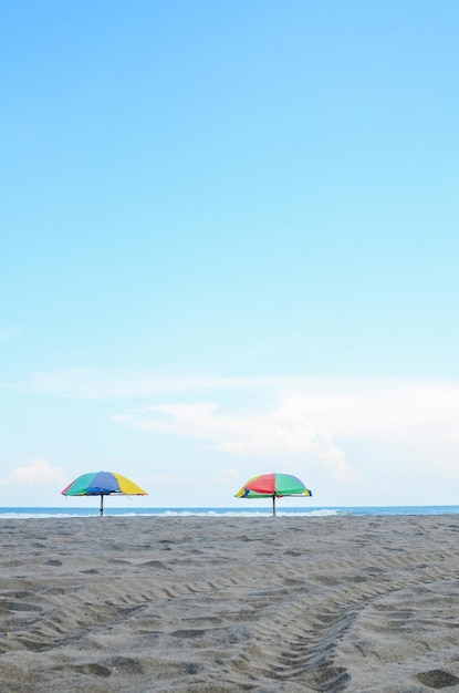 Dos sombrillas de colores en una playa solitaria