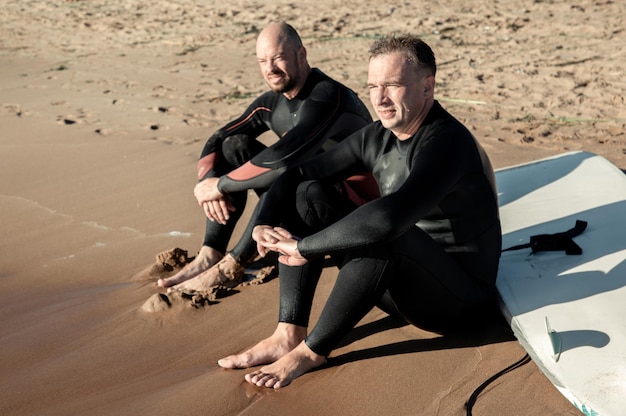 dos surfistas se sientan en la playa