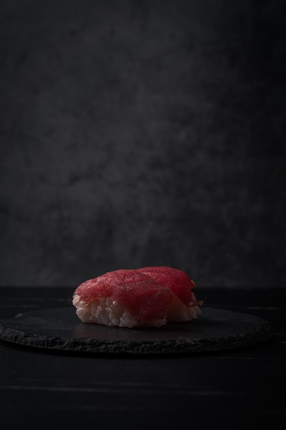 Dos sushi de atún crudo sushi en plato negro y fondo de mesa negro