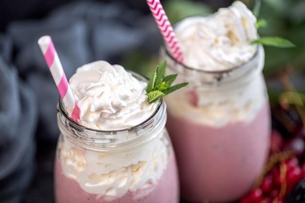 Dos tarros de batido o batido con arándanos, fresas y arándanos sobre la superficie de piedra