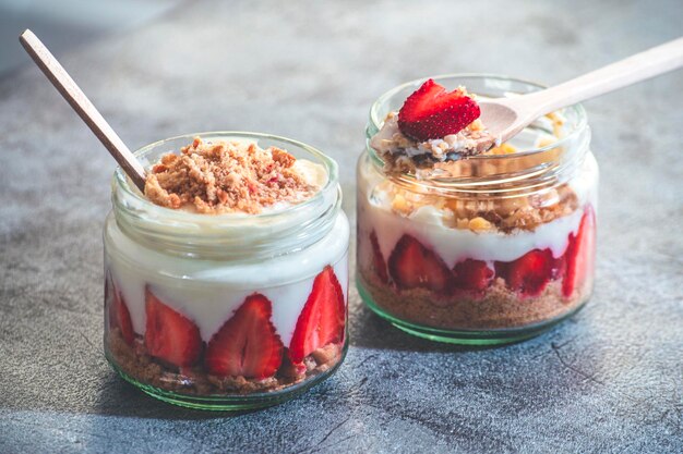 Dos tarros de postre de magnolia con pudín de fresa sobre un fondo rústico