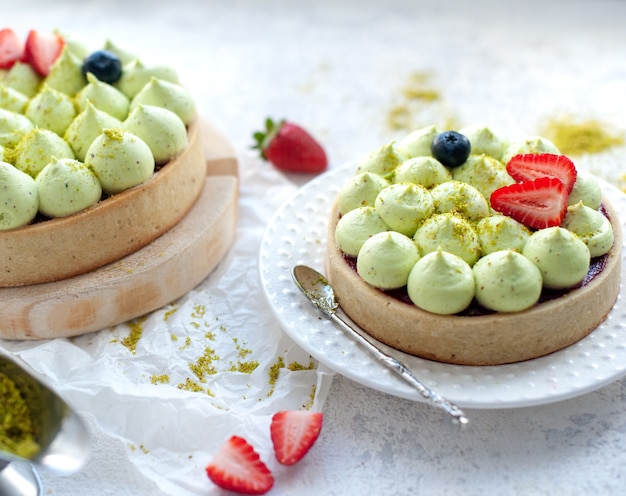 Foto dos tartas de galletas redondas con crema de pistacho verde y mermelada de fresa, close-up