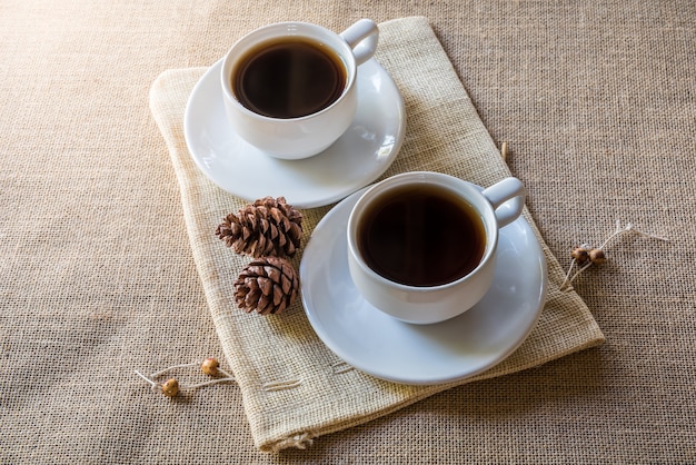 dos taza de café y pino conos en saco de cilicio