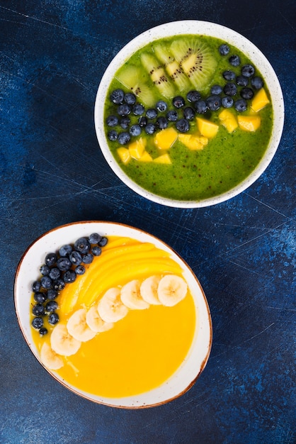 Dos tazas de batido diferente tazón de frutas verdes y amarillas. El concepto de alimentación saludable. Foto vertical. Vista superior.