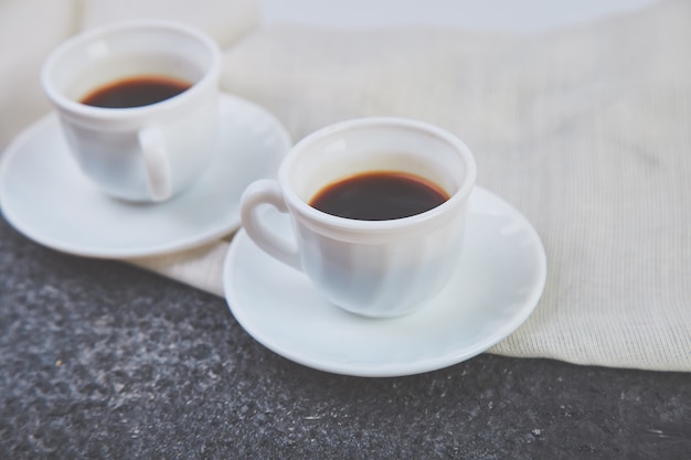 Dos tazas blancas de café exprés en grunge gris.