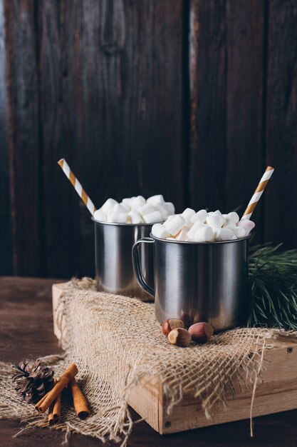 Dos tazas con cacao y malvaviscos sobre un fondo marrón