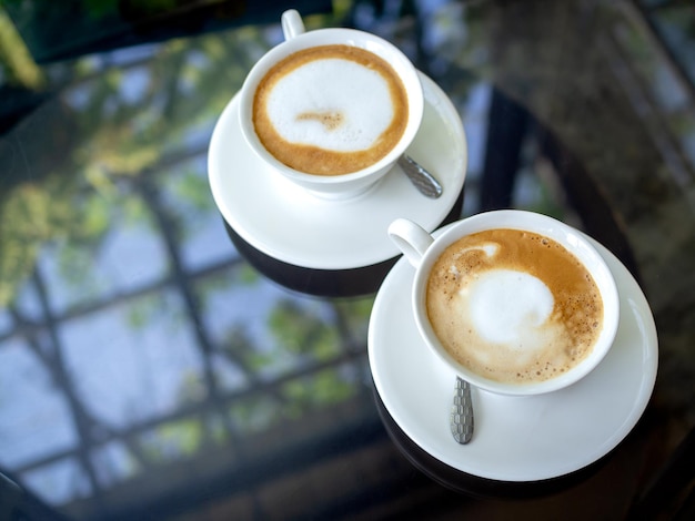 Dos tazas de café de cerámica blanca sobre una mesa de cristal