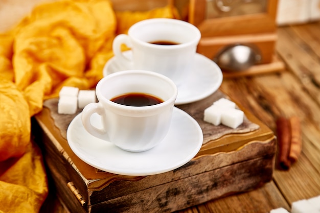 Dos tazas de café expreso cerca del terrón de azúcar en la mesa de madera rústica.